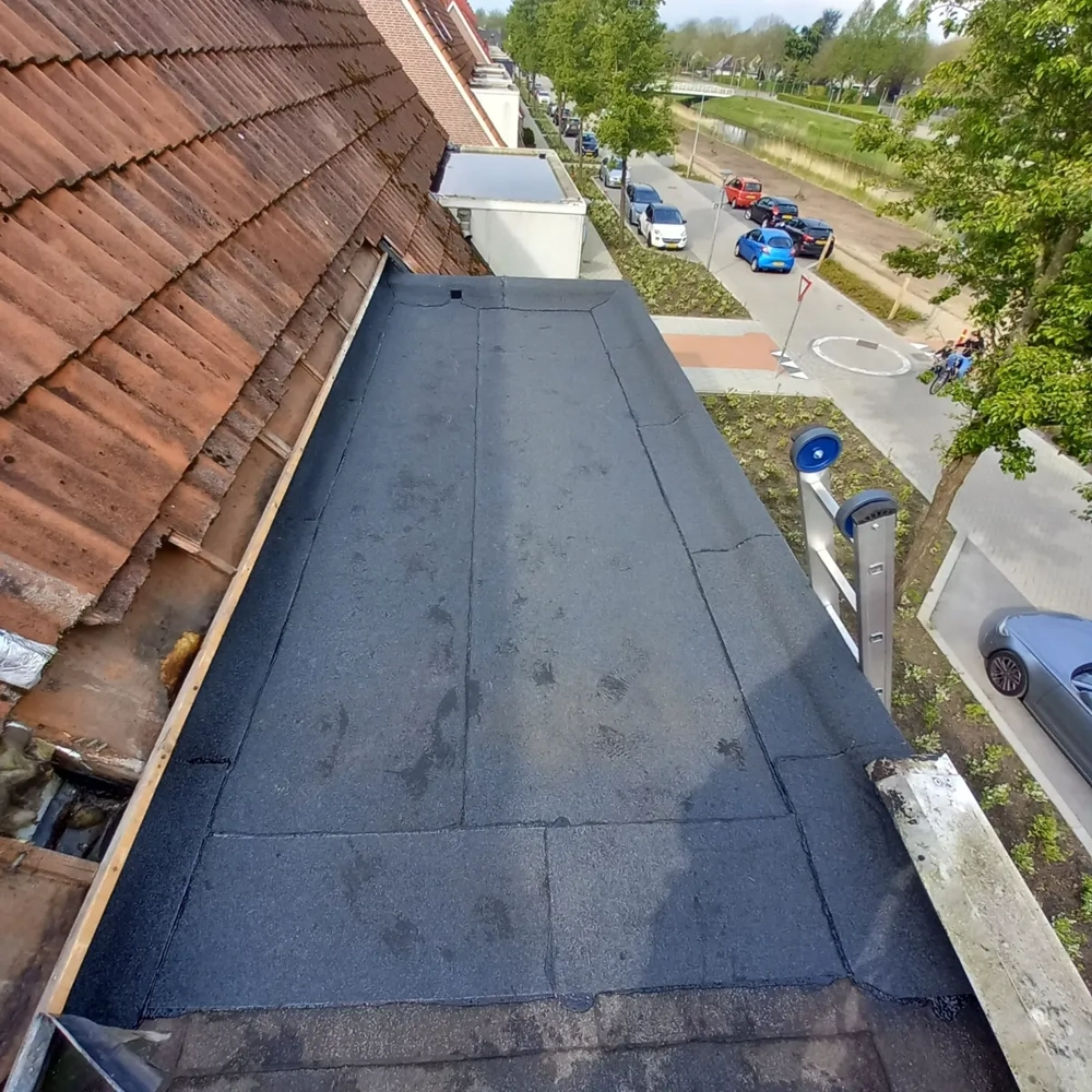 Zwart bitumen op een gerenoveerd plat dak bij een woning als voorbeeld van Platte daken