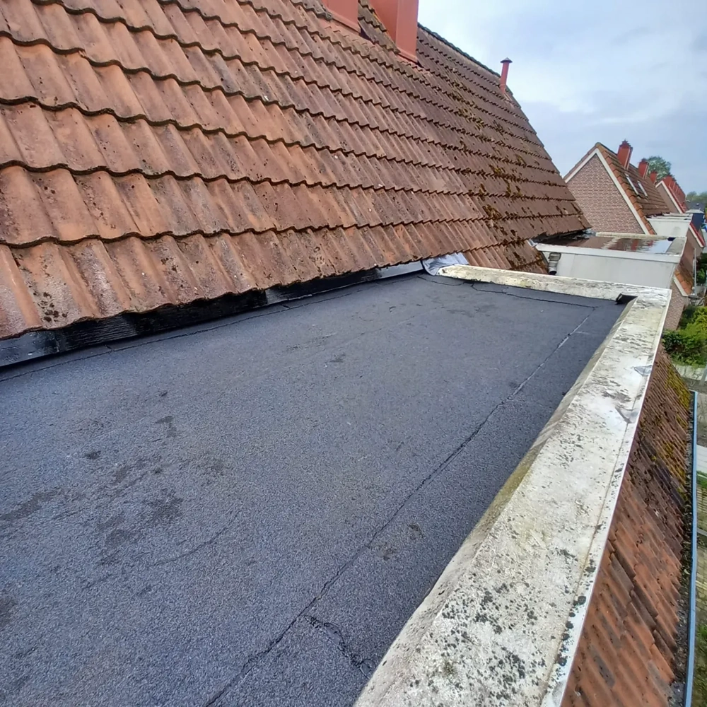 Nieuw aangelegde bitumen dakbedekking op plat dak naast keramische dakpannen Platte daken