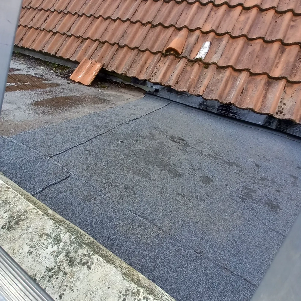 Platte daken met zwarte bitumen dakbedekking naast hellend dak met keramische dakpannen