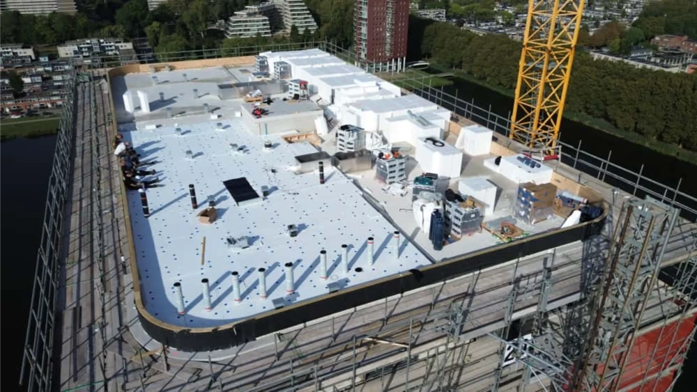 Plaatsing platte daken met witte PVC-folie, isolatieblokken en dakdoorvoeren op bouwproject