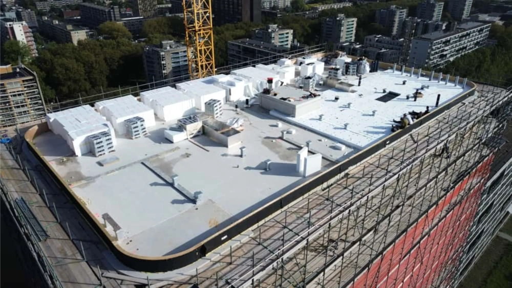 Vlak dak met witte dakbedekking en isolatieblokken bij dakrenovatie op hoogbouw