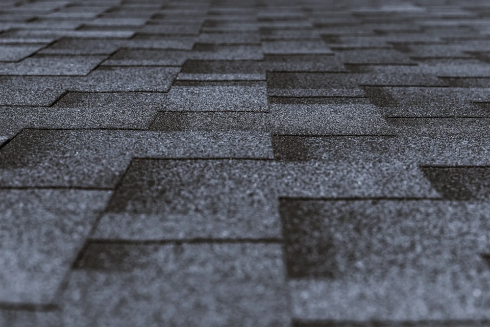 Close-up van donkere bitumen shingles op hellend dak, strak en waterdicht afgewerkt