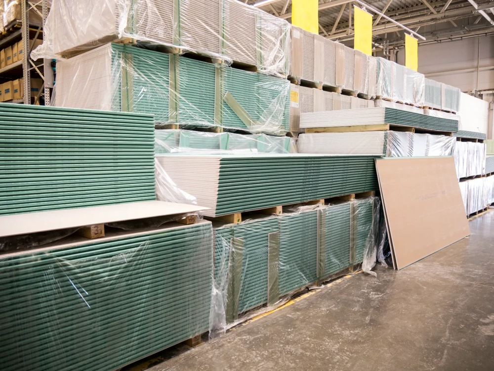 Stapels groene gipsplaten op houten pallets in magazijn