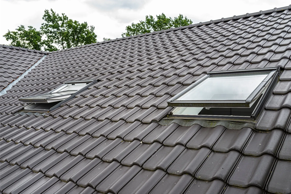 Twee geopende dakramen gemonteerd in zwart dak met keramische dakpannen